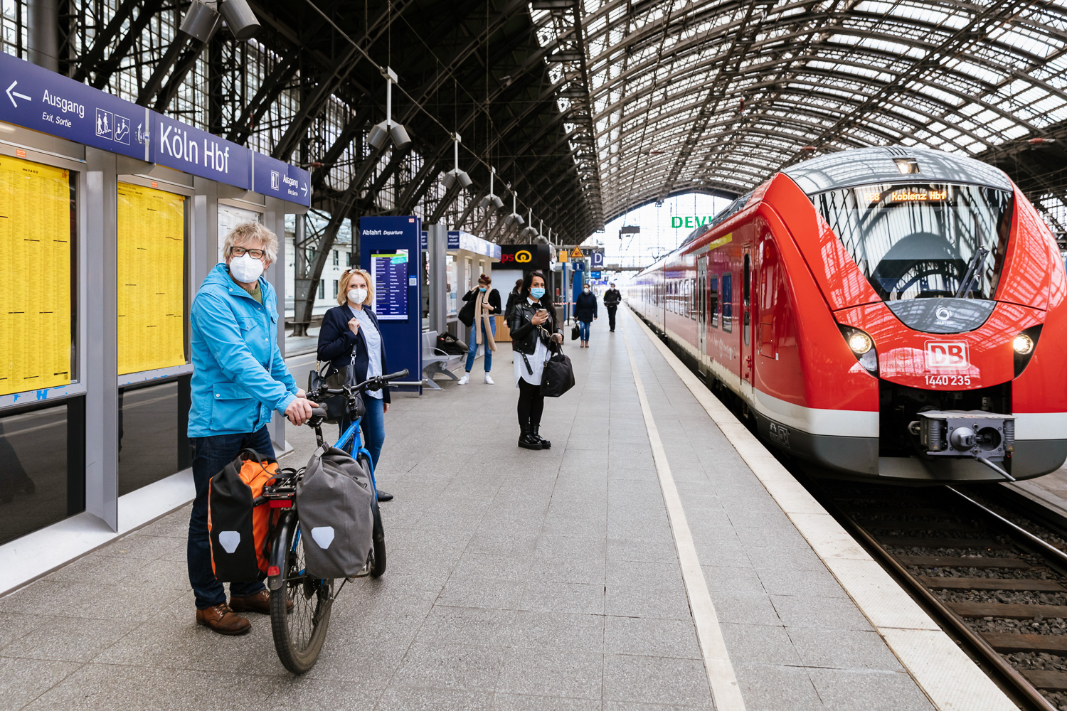 Wir sehen einen Radfahrer am Bahnsteig, während ein Zug einfährt.