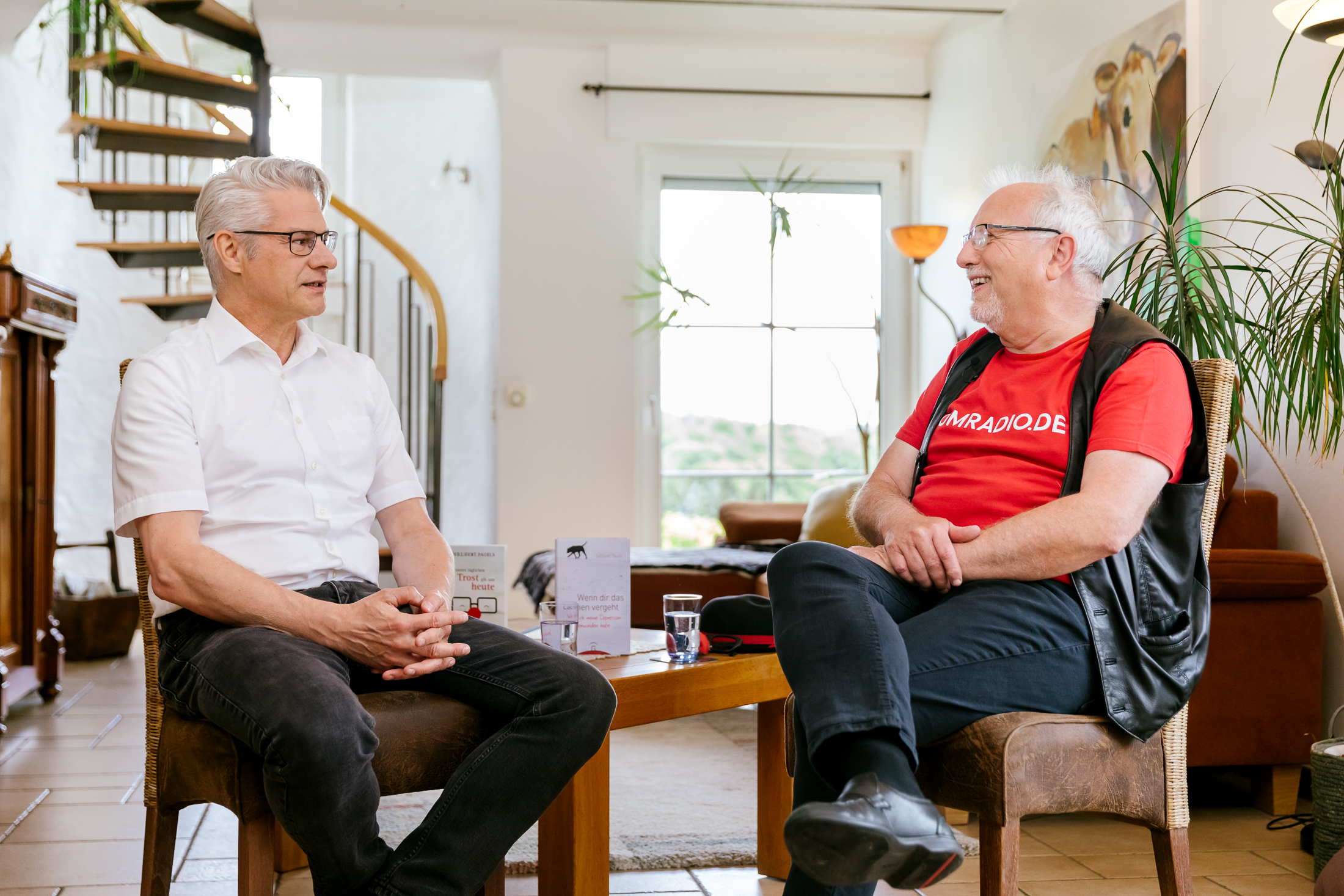 Ein Bild zeigt Michael Vogel und Willibert Pauels, wie im Wohnzimmer von Herrn Pauels zusammensitzen und sich rege austauschen.